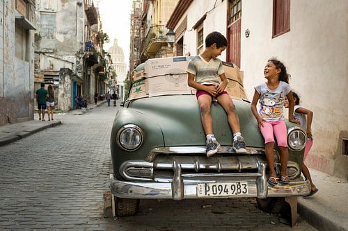 Enfants jouant sur une voiture cubaine