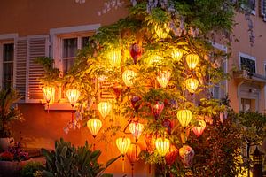 Des lampions colorés et lumineux sur le mur d'une maison