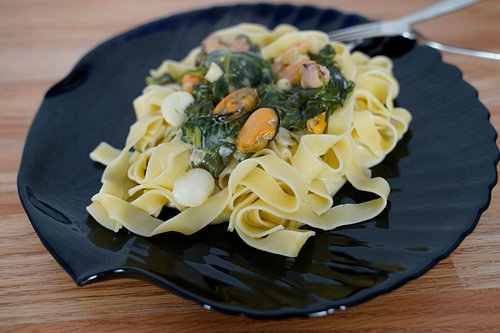 Fettuccini met spinazie en kaas roomsaus en zeevruchten geserveerd op een bord