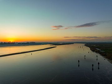 Schaatsen op een meer tijdens een prachtige winterse zonsondergang van Sjoerd van der Wal Fotografie