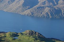 Small boat between high mountain walls on Lake Wanaka in New Zealand