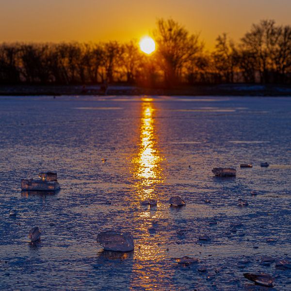 Chunk of ice on a frozen lake during a warm sunrise by Kim Willems