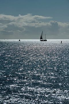 Bateau à voile contre l'éblouissement du soleil dans la mer des Wadden près de l'île de Terschelling sur Tonko Oosterink