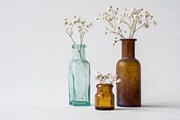 Drie antieke vaasjes op witte achtergrond met takjes gedroogd gipskruid. Minimalistisch beeld met re