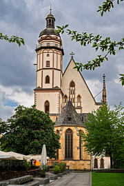 L'église Saint-Thomas de Leipzig, au milieu des arbres verts, sous les nuages sur ManfredFotos