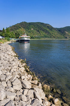 Weiße Felsbrocken und ein Kreuzfahrtschiff am Rheinufer in Boppard