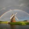 grote dubbele regenboog boven Nederlandse windmolen in zomerregen van Olha Rohulya