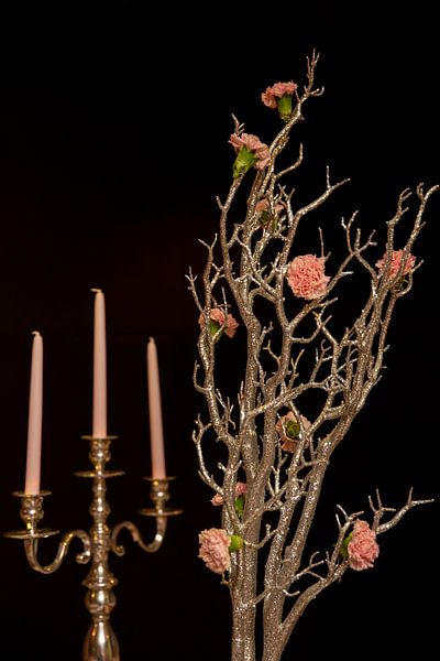 Vintage Kerzenständer mit Kerzen und rosa Blumen auf schwarzem Hintergrund. Stilleben Blumenarrangement von Helga Golubew