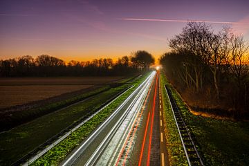 Zons ondergang en lichtsporen op de weg van Rob Baken