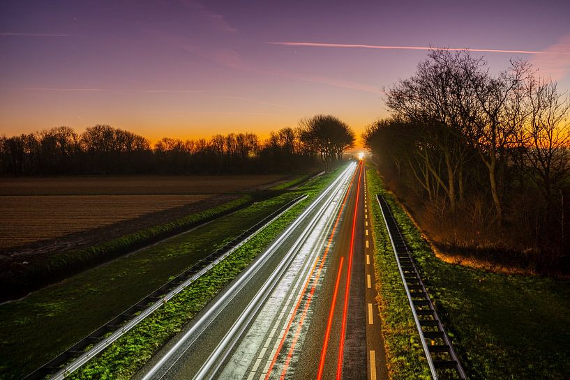 Coucher de soleil et traînées lumineuses sur la route par Rob Baken