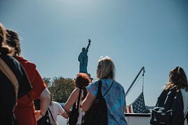 Statue of Liberty behind tourists by Erwin van Kester