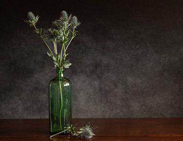Un bouquet de chardons dans une bouteille verte sur Irene Ruysch