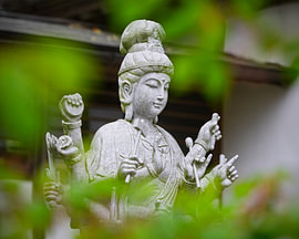 Zen-Guanyin-Statue durch grünes Laub von Gayane Nakada