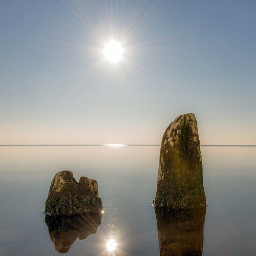 Oude golfbrekers in het IJsselmeer gespiegeld in het stilstaande water