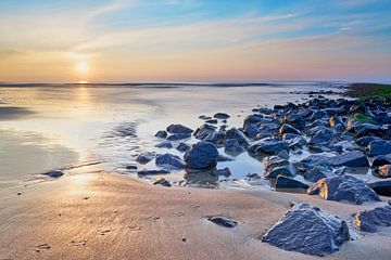 Golfbrekers met strand bij een zonsondergang van eric van der eijk