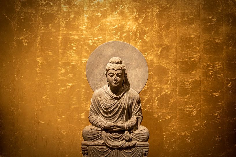 Buddha statue in front of golden wall in meditation seat by Alexander Baumann
