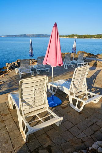 Parasols en ligstoelen op het strand van Krk in het Kroatisch