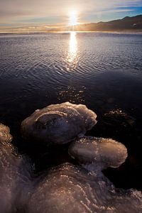 Des morceaux de glace sur les pierres, l'eau et le soleil levant