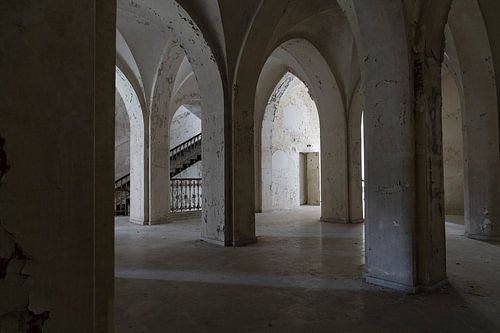 Hal in vervallen klooster met bogen en trap