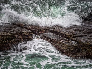 Golven breken op een rotsachtige kust van Luc de Zeeuw