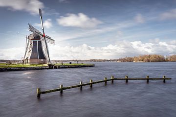 Holländische Windmühle an einem See mit dynamischer Wolkenlandschaft