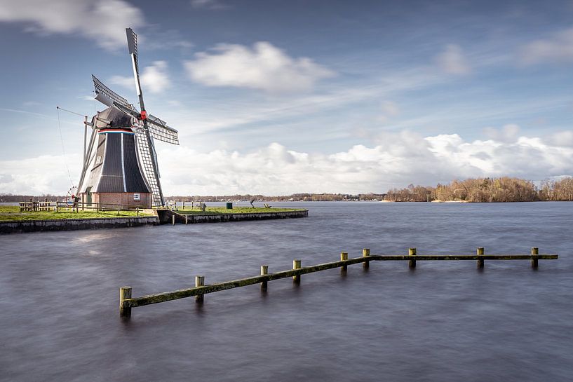 Holländische Windmühle an einem See mit dynamischer Wolkenlandschaft von Fotografiecor .nl