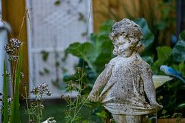 Stenen beeldje van een meisje in de achtertuin van Pim Coenraads