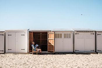Man reads newspaper in front of beach house