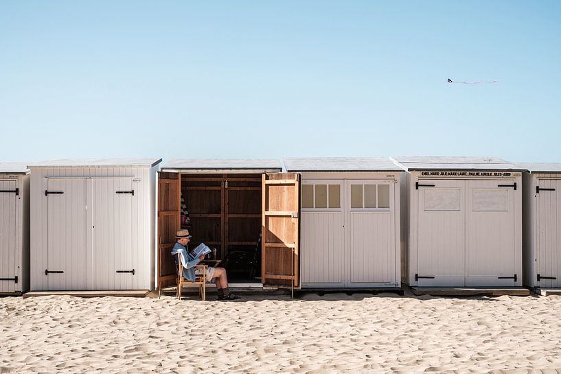 Mann liest Zeitung vor einem Strandhaus von Jack Tummers