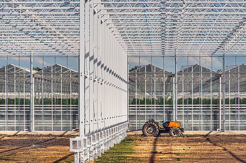 A greenhouse under construction with a red tractor stationed in it