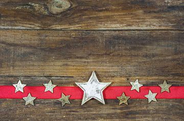 Christmas stars ornaments on red ribbon border decoration on rustic wooden background, copyspace by Alex Winter