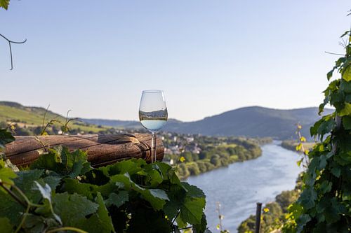 Filled wine glass next to wooden beams and Moselle landscape in the background