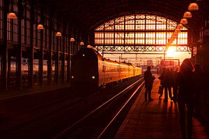 Silhouetten van wachtende reizigers op treinstation tijdens zonsondergang
