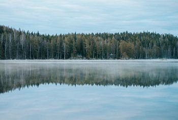 Hütten am Rande eines nebligen Sees in Schweden