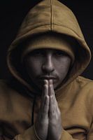 Portrait Young man with hoodie squeezes hands together