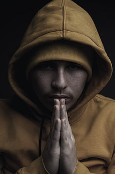 Portrait Young man with hoodie squeezes hands together