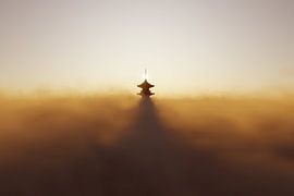 Eine traditionelle Pagode, die sich bei Sonnenuntergang über die Wolken erhebt