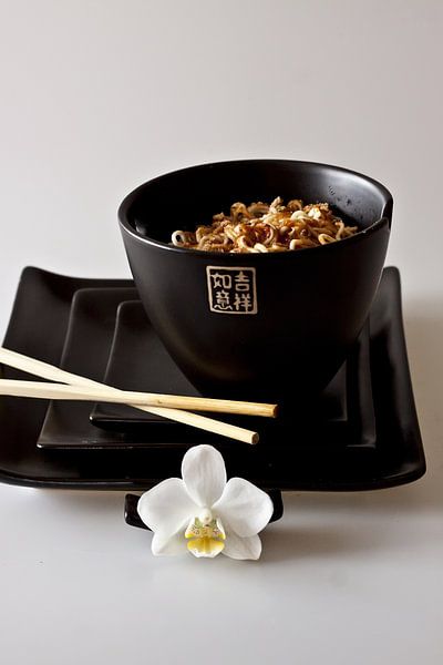zwarte Chinese kom en gestapelde borden met eetstokjes en orchidee als detail gevuld met noodles als von Margriet Hulsker