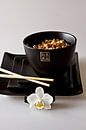zwarte Chinese kom en gestapelde borden met eetstokjes en orchidee als detail gevuld met noodles als van Margriet Hulsker thumbnail