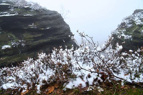 Zschirnstein with snow-covered rocks and fog on the summit