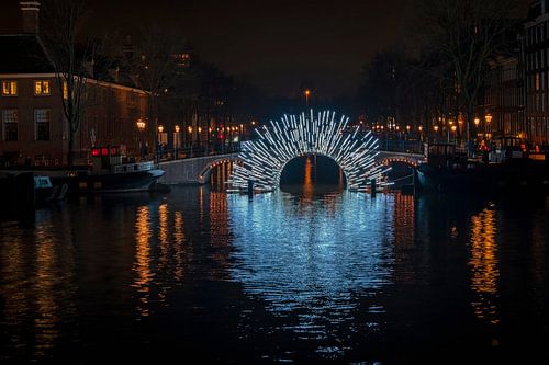 Verlichte brug aan rivier de Amstel in Amsterdam Nederland bij avond