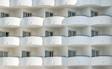 Nahaufnahme der Hotelarchitektur mit Balkon und Fenstern eines weißen Tourismusgebäudes von Alex Winter