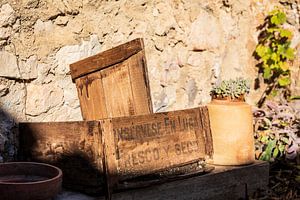 wooden crate against stone wall in sunshine von VIDEOMUNDUM