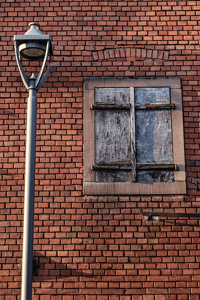 Muur met grijsblauw luik en lantaarnpaal van Stadspronk
