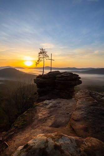 De Rötzenfels, een landschapsopname van een zandsteenrots met een kruis en een boom, zonsopgang met 