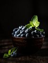 Blauwe bessen met muntblaadjes in bruine kom van Iryna Melnyk thumbnail