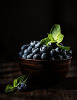 Blaubeeren mit Minzblättern in brauner Schale