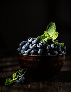 Myrtilles avec feuilles de menthe dans un bol brun sur Iryna Melnyk