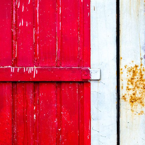 Motif de lignes abstraites sur panneau de porte rouge, usé par les intempéries