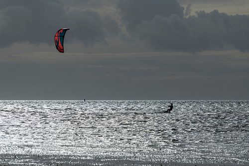 Sporty kitesurfer in the evening sun on the Wadden Sea near the island of Terschelling in the north 